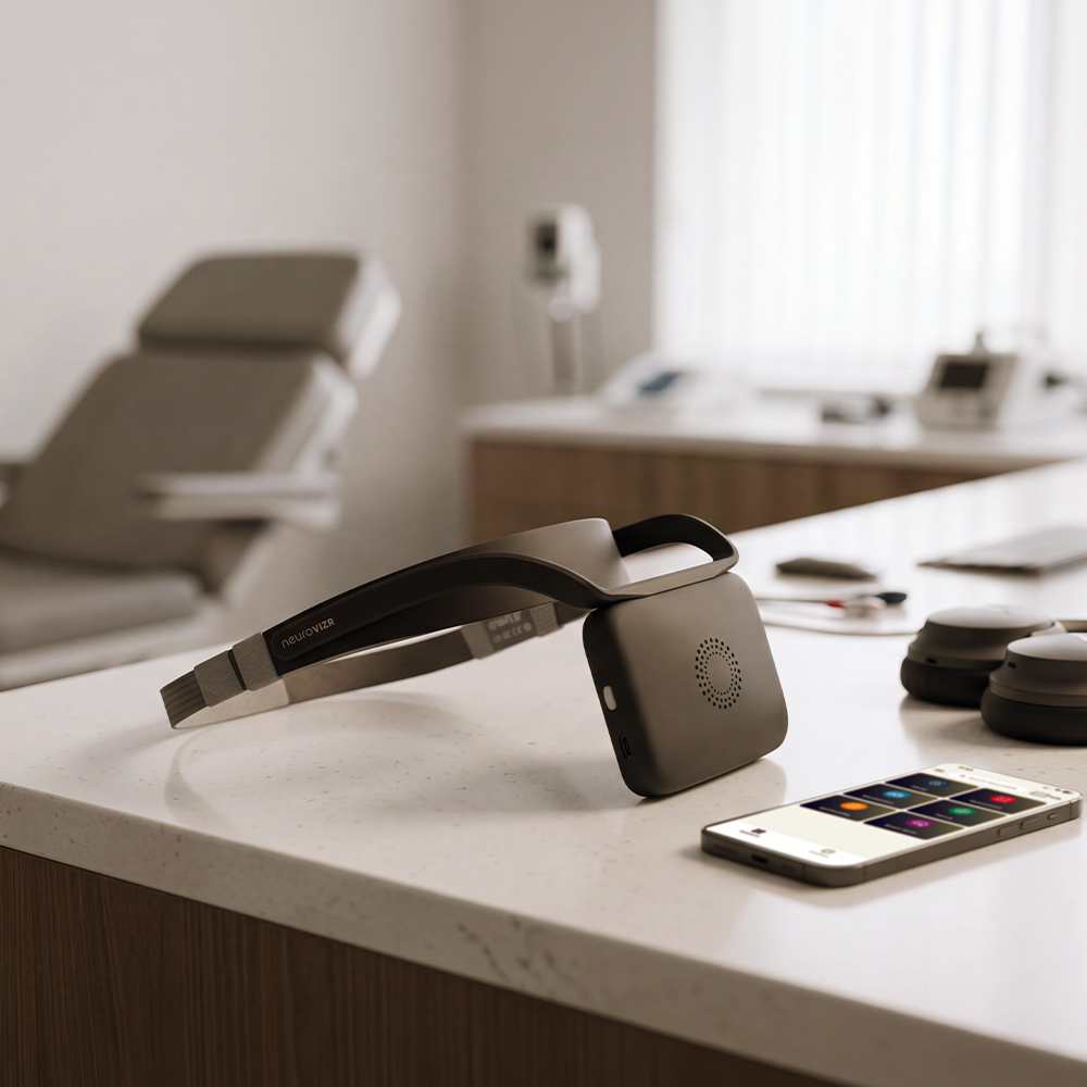 NeuroVIZR Original in Space Grey resting on a counter beside a phone running the NeuroVIZR app