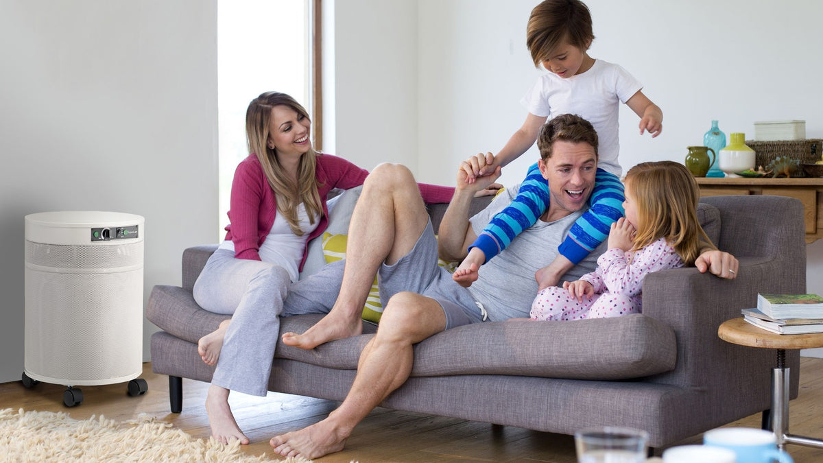 Family on a sofa at home with an Airpura air purifier for smoke and wildfire season
