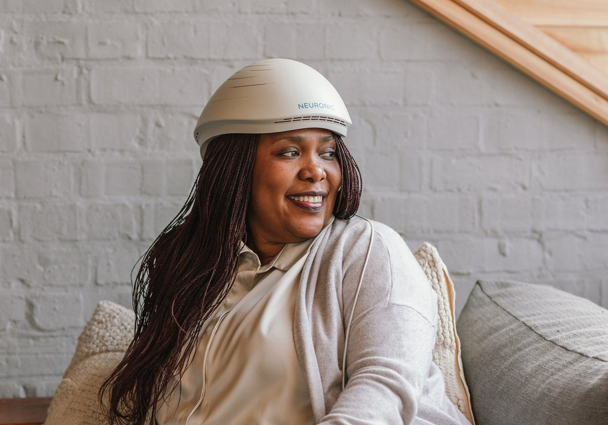 Woman wearing the Neuronic LIGHT brain light helmet on a sofa at home