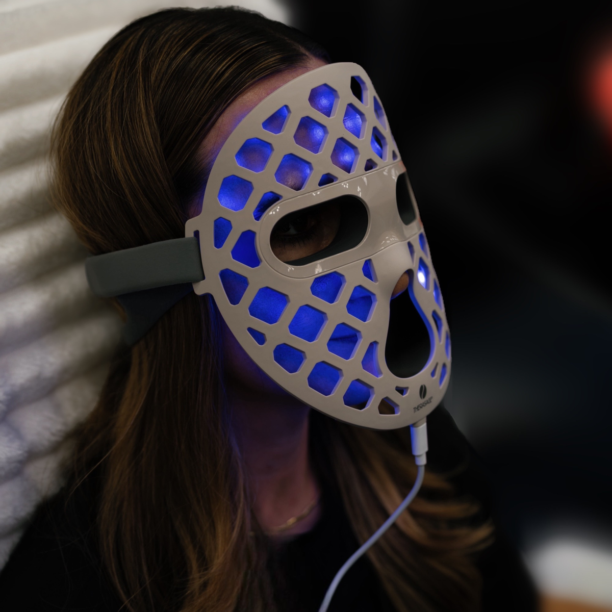 Woman wearing the TheraGlow Mask2Go+ in blue light mode