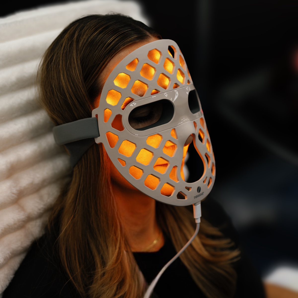 Woman wearing the TheraGlow Mask2Go+ in yellow light mode
