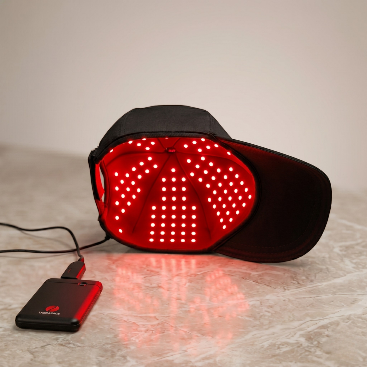 TheraCap with its red LED lining lit, connected to the power bank
