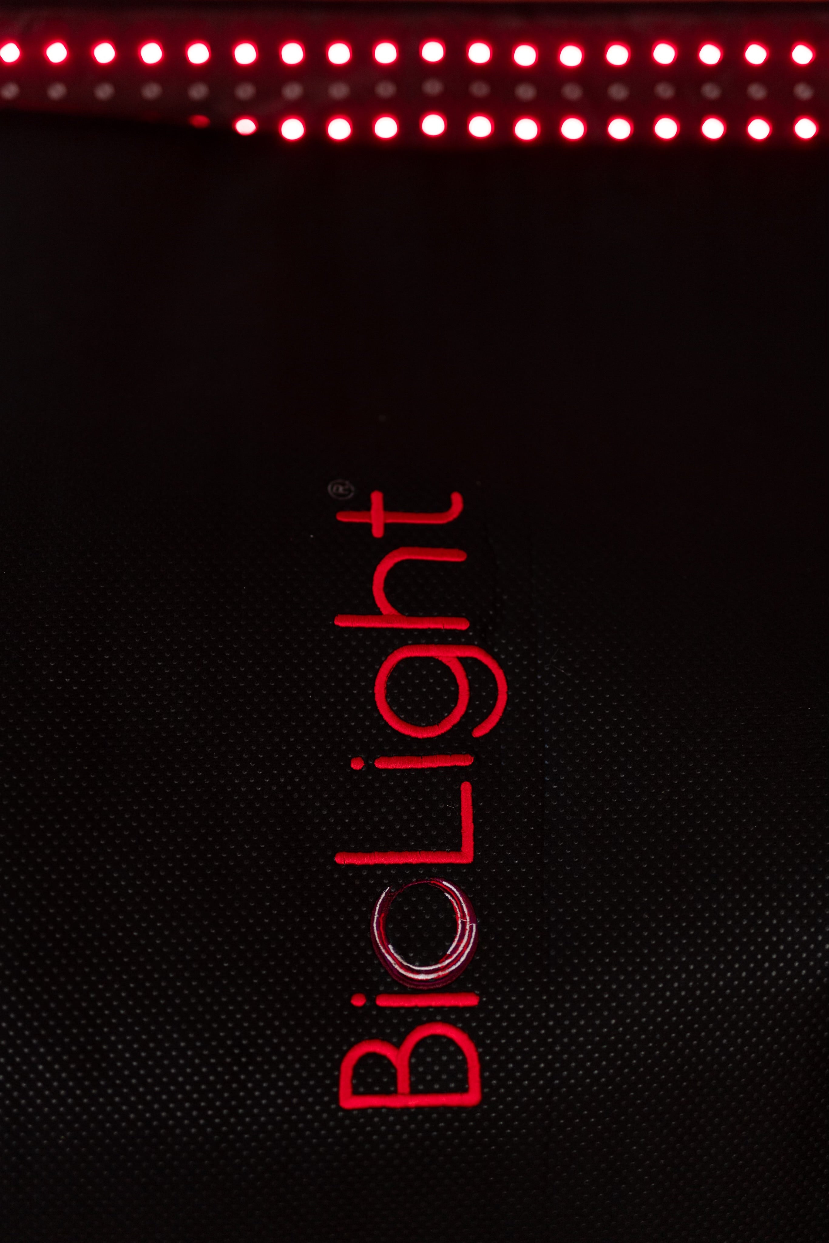Close-up of the red embroidered logo on the BioLight Cocoon pod's black cover, LED row lit above