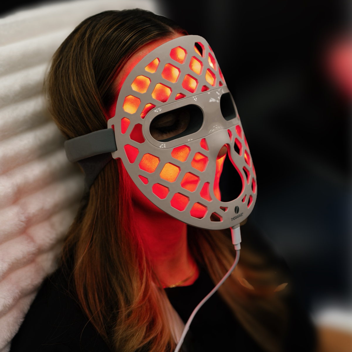 Woman relaxing in the TheraGlow Mask2Go+ in red light mode, side view