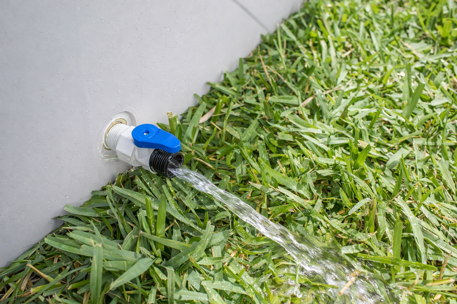 Frozin 400 white granite drain valve open, water draining onto grass #Color_White Granite