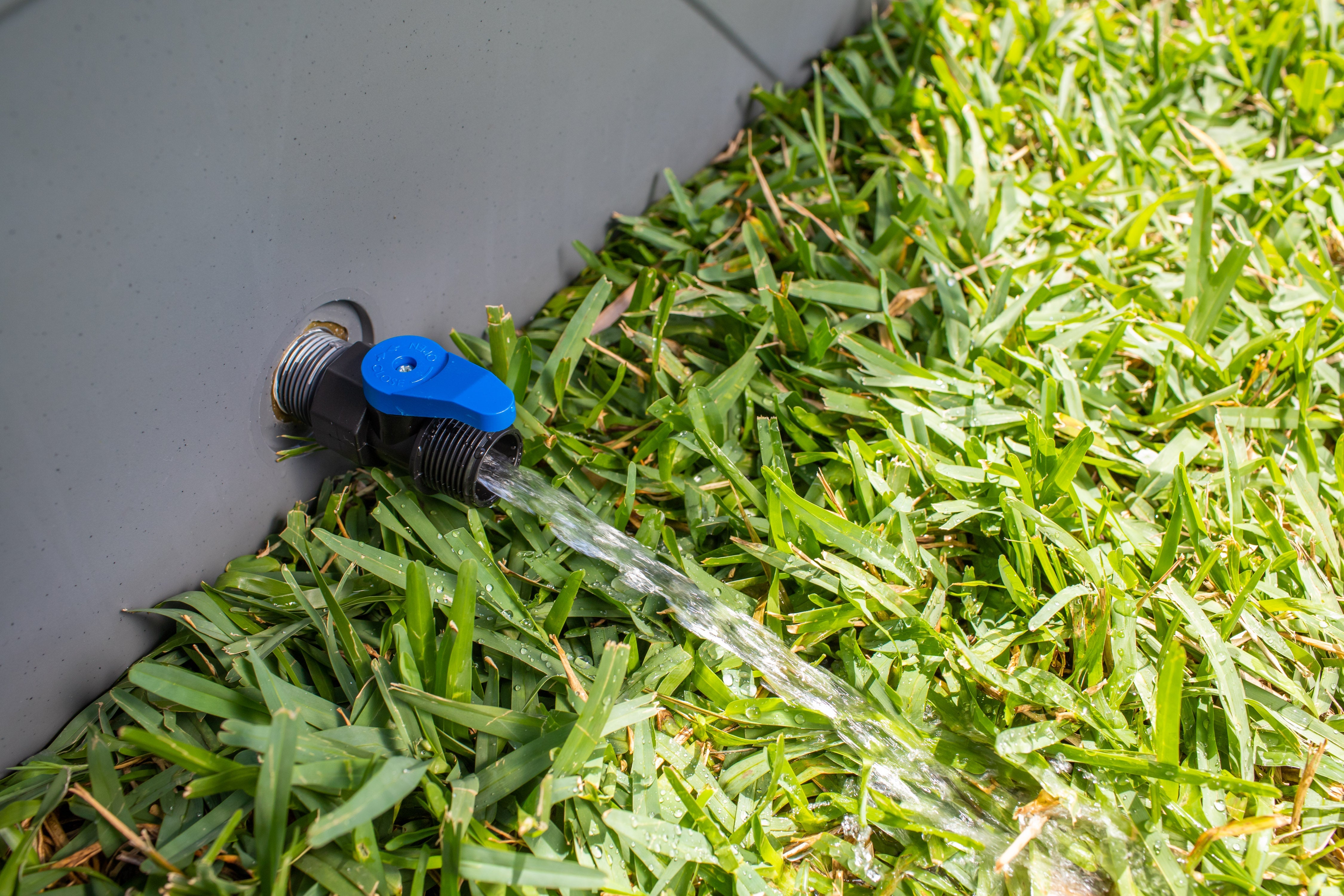 Frozin 400 grey granite drain valve open, water draining onto grass #Color_Grey Granite