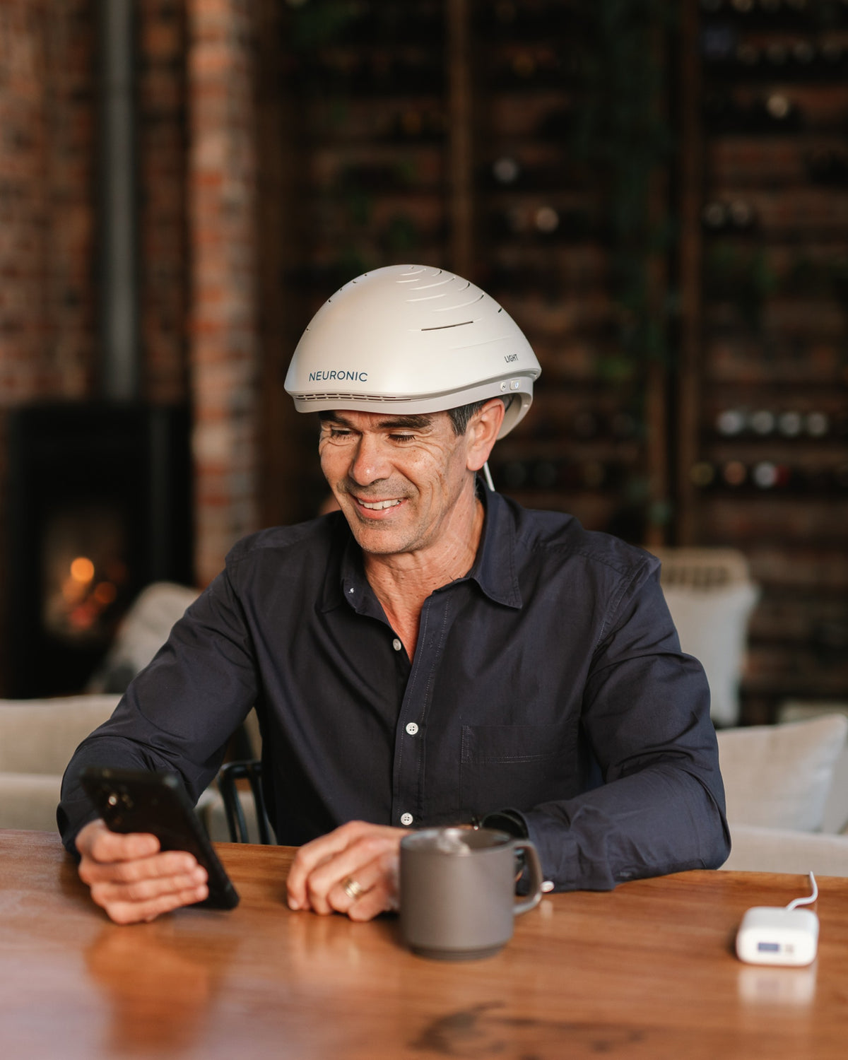 Man wearing the Neuronic LIGHT at a table, starting a session from his phone
