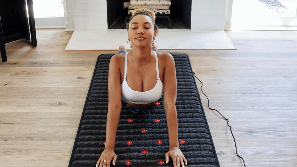 Woman stretching on a PEMF therapy mat during a home recovery session