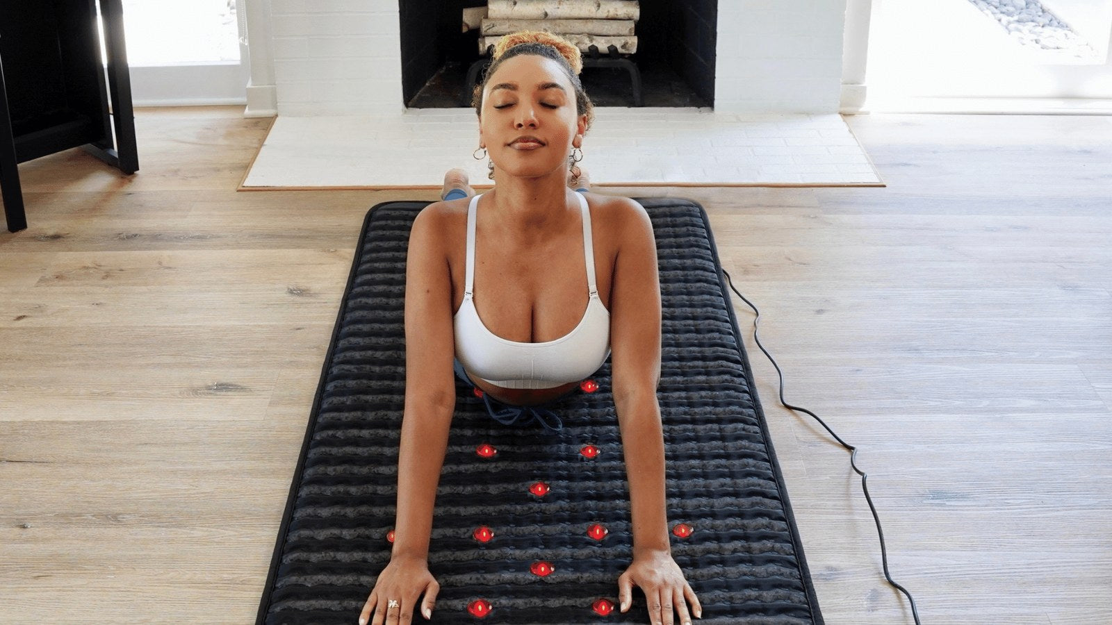 Woman stretching on a PEMF therapy mat during a home recovery session