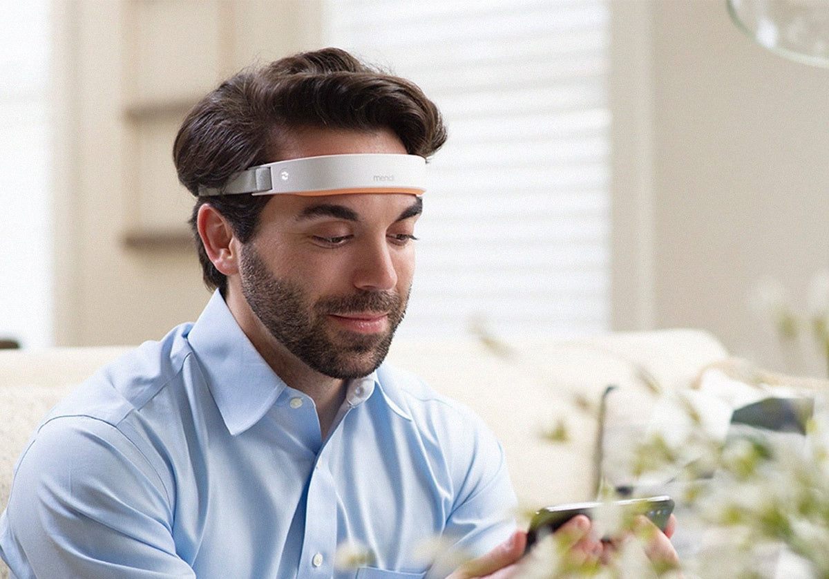 Man wearing the Mendi Headset on his forehead while following a focus session on his phone