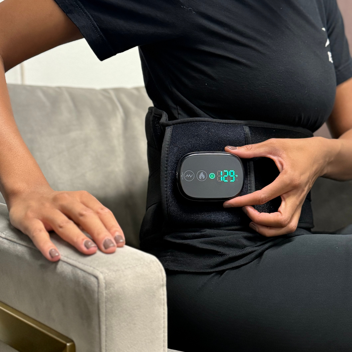 Person wearing the TheraBelt around the lower back over a T-shirt, adjusting the controller