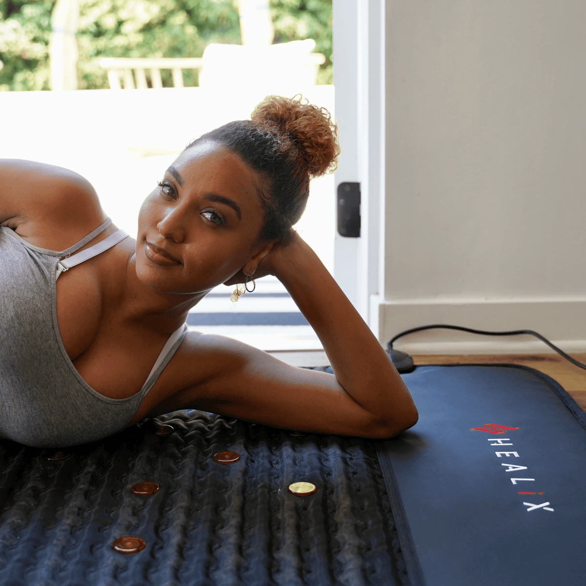 HEALiX Revive PEMF Mat lifestyle, woman resting on her side on the mat