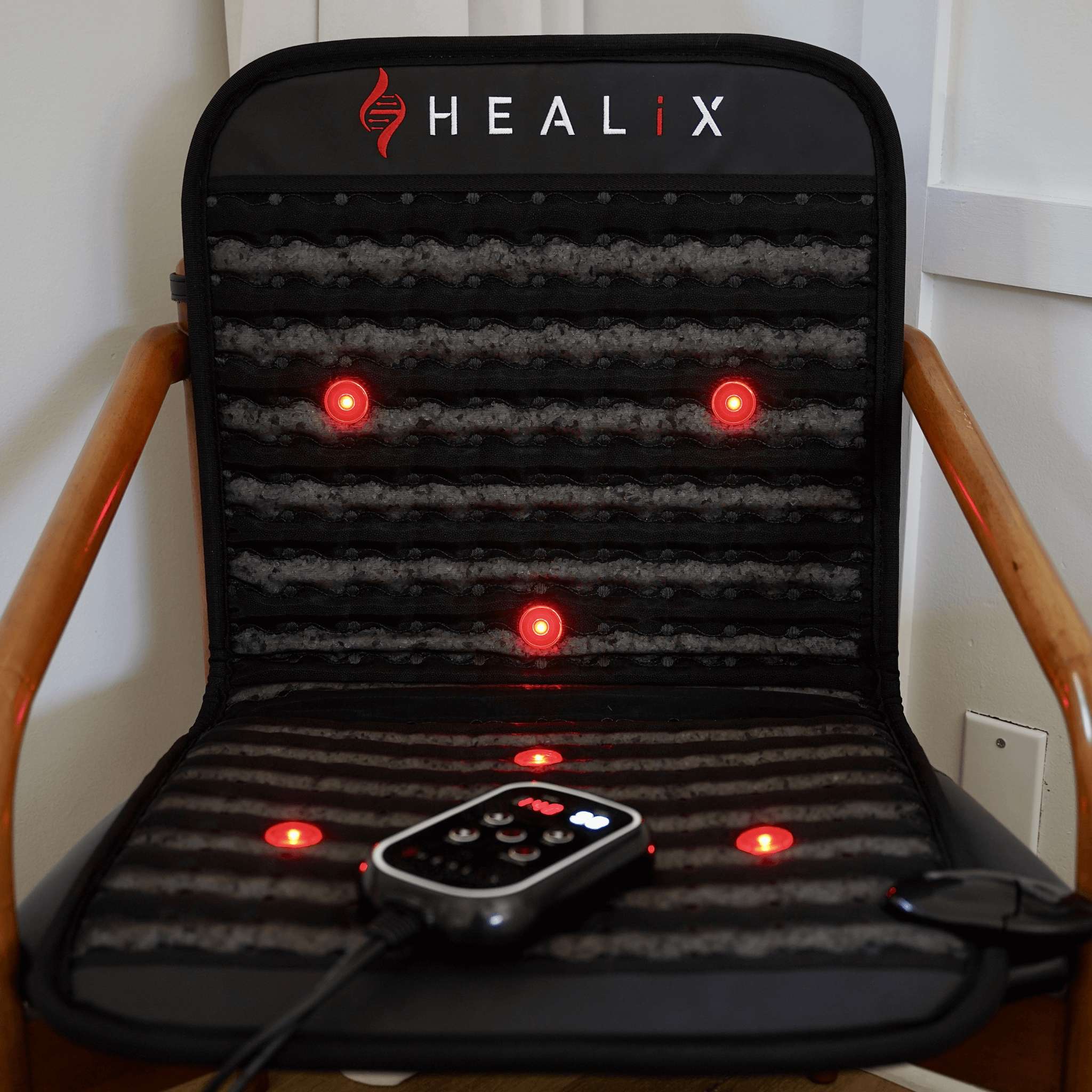 HEALiX Revive Mini PEMF Mat on a chair with red lights on and corded controller