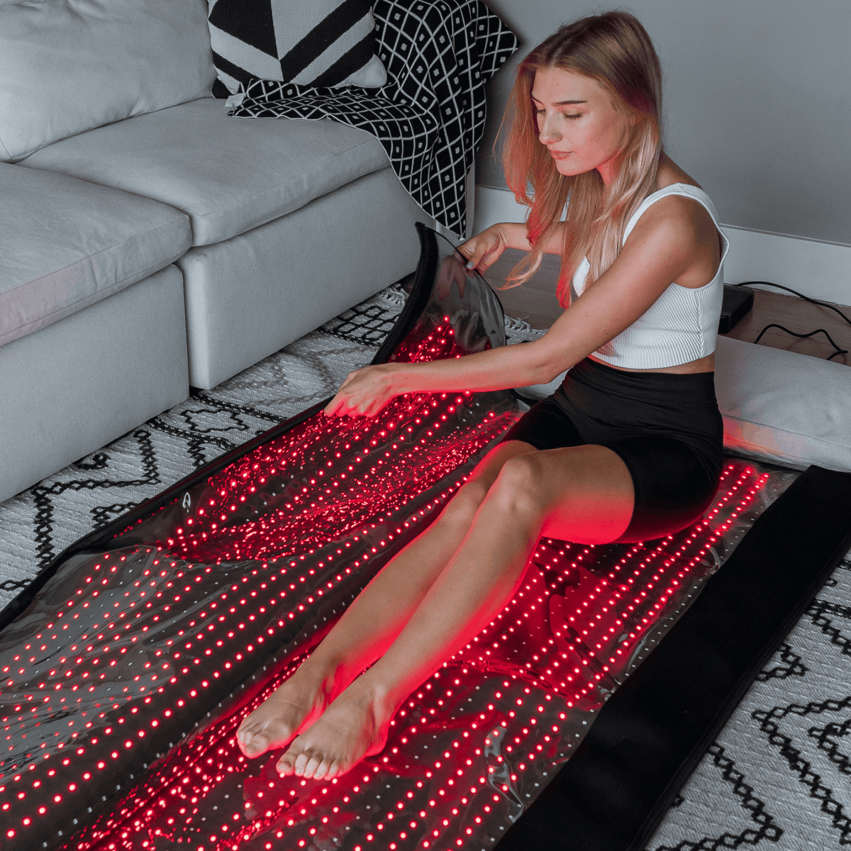 HEALiX Glow Pod on the living room floor, seated with legs under red light