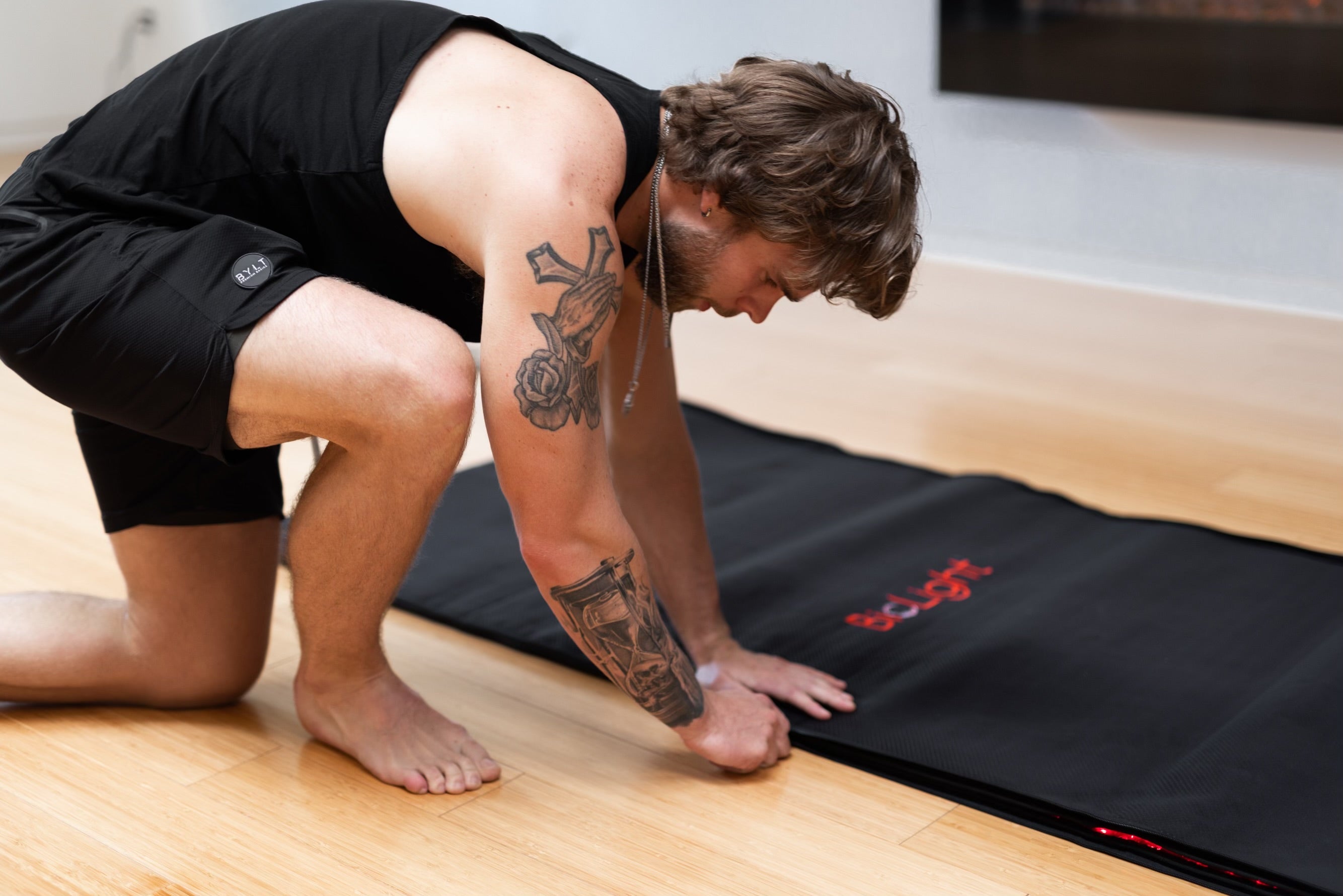 Man kneels beside the closed BioLight Cocoon pod, pressing the black outer cover flat on the floor