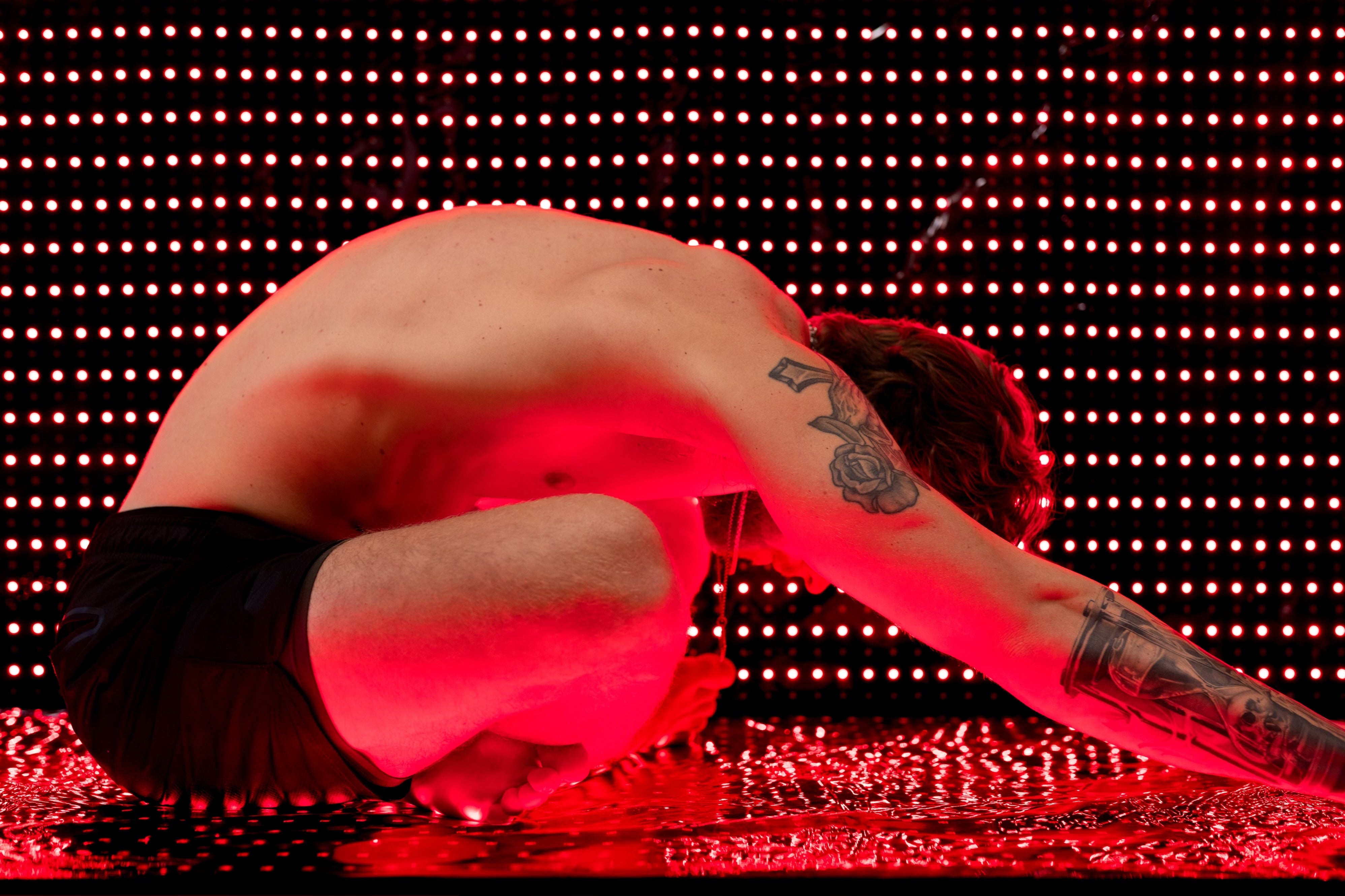 Man rests in child's pose on the BioLight Cocoon pod with its red LED panel lit behind him