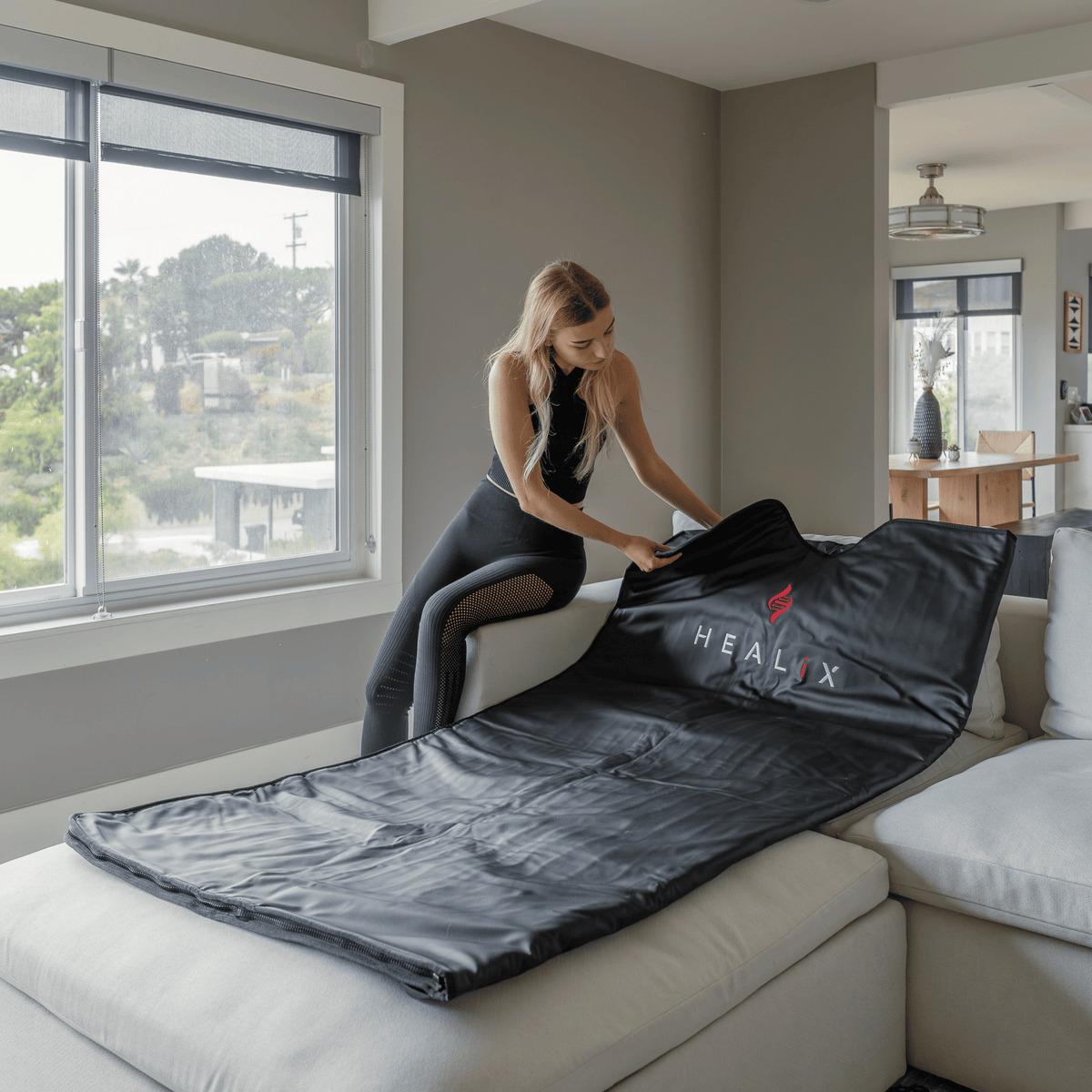 HEALiX-Z Infrared Sauna Blanket being spread out on the couch by the window
