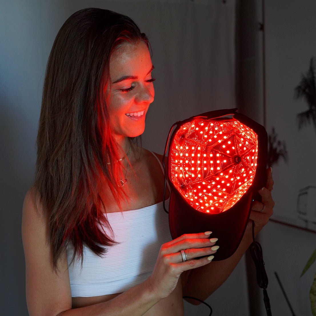 Woman holding the TheraCap with its LED lining lit red