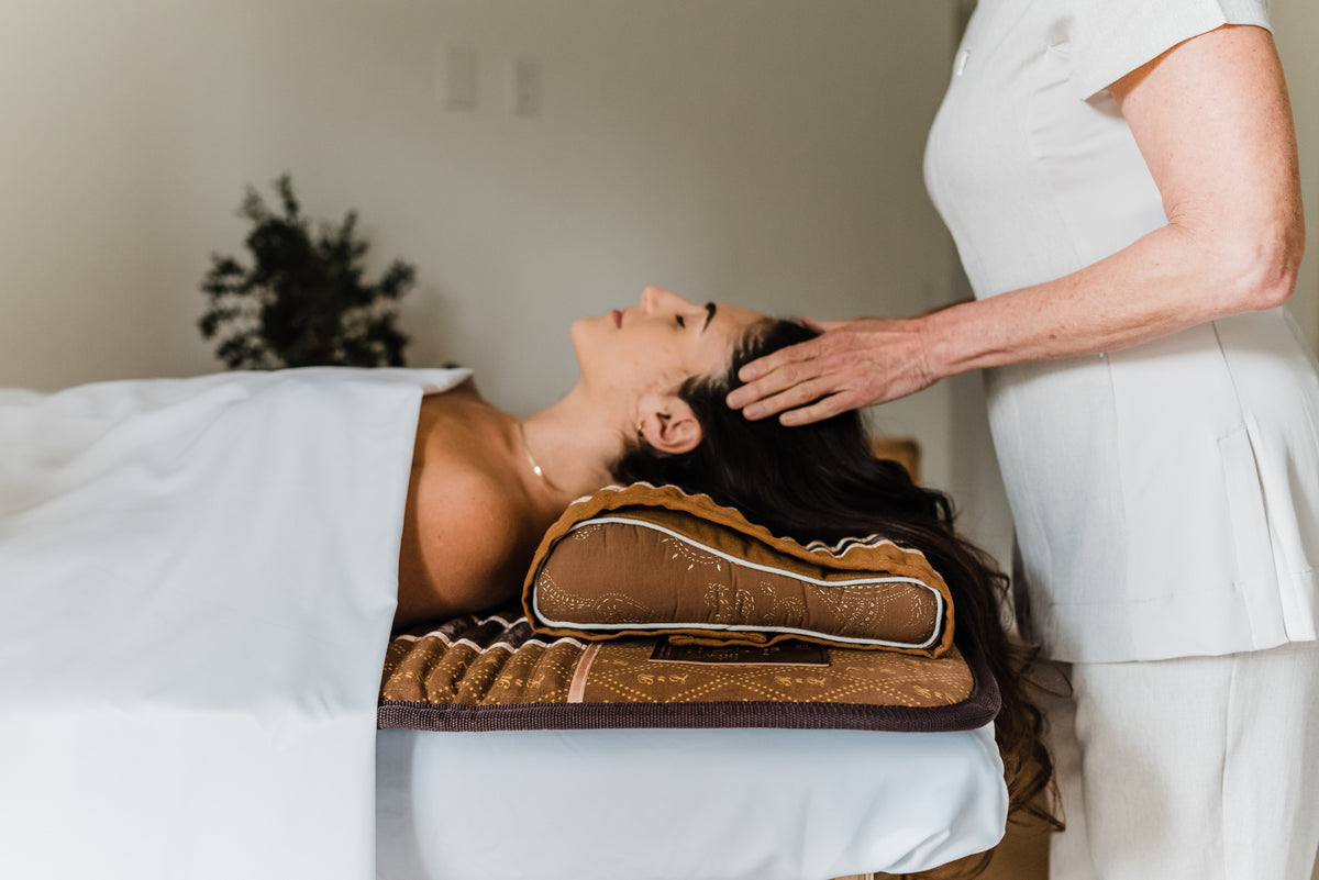 Client resting on the BioMat Pro and Pillow during a practitioner session