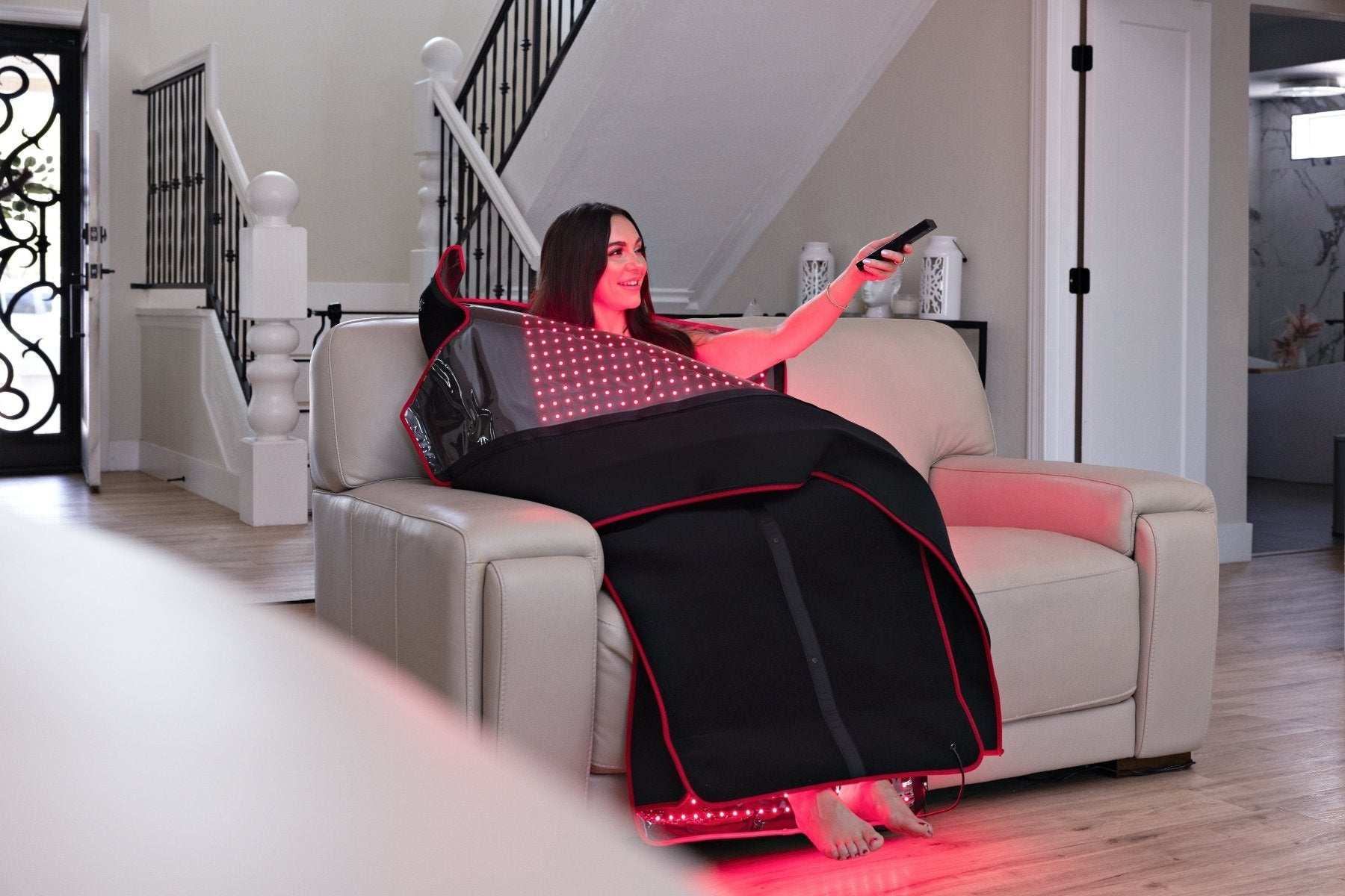 MitoPOD reclined session with remote in hand and red glow at the feet