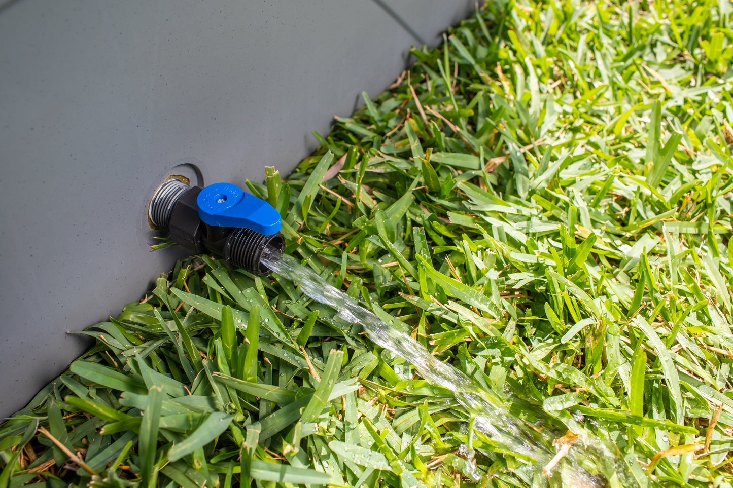 Frozin 400 grey granite drain valve open, water draining onto grass #Color_Grey Granite
