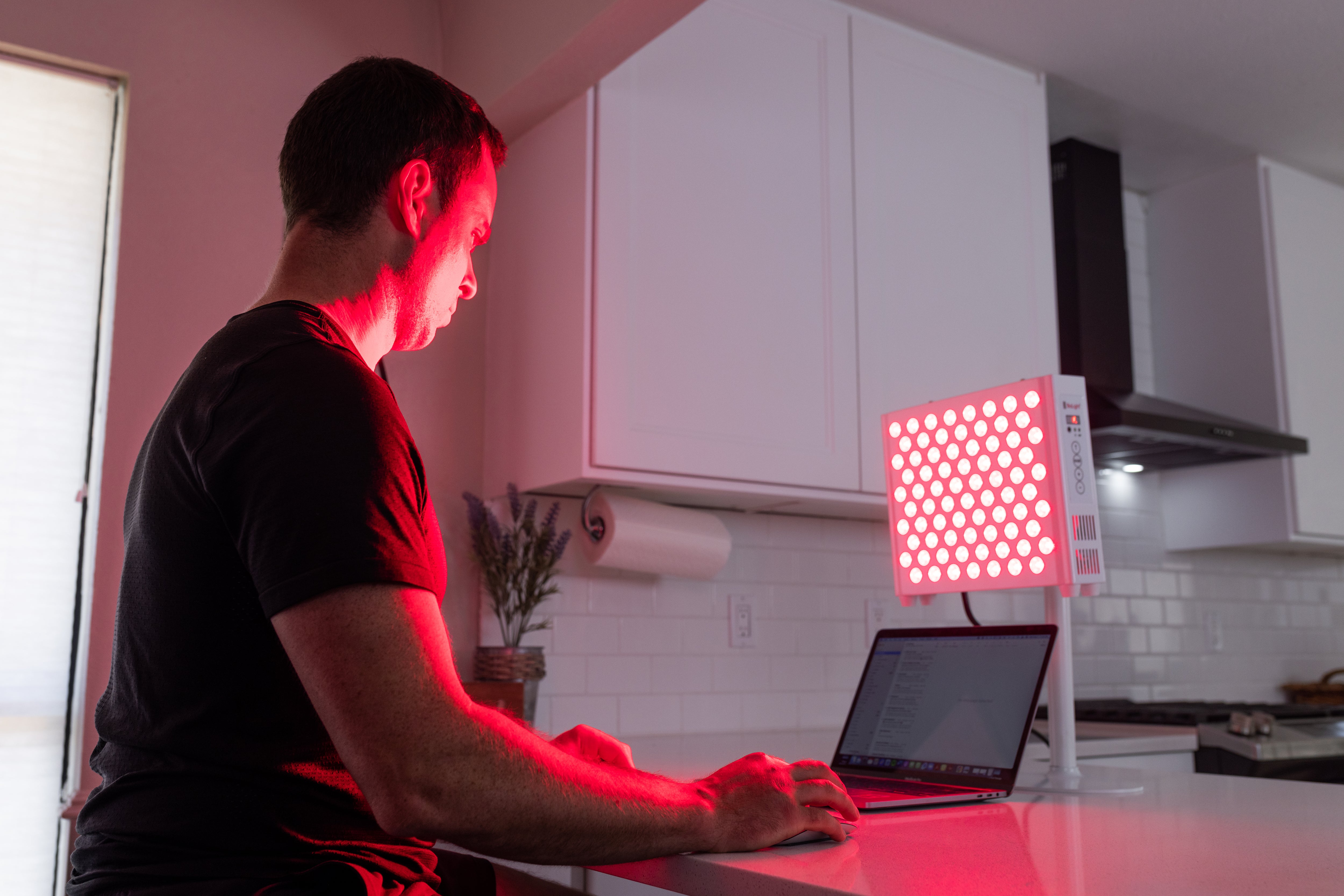 BioLight ReCharge panel lit on a kitchen counter next to a laptop